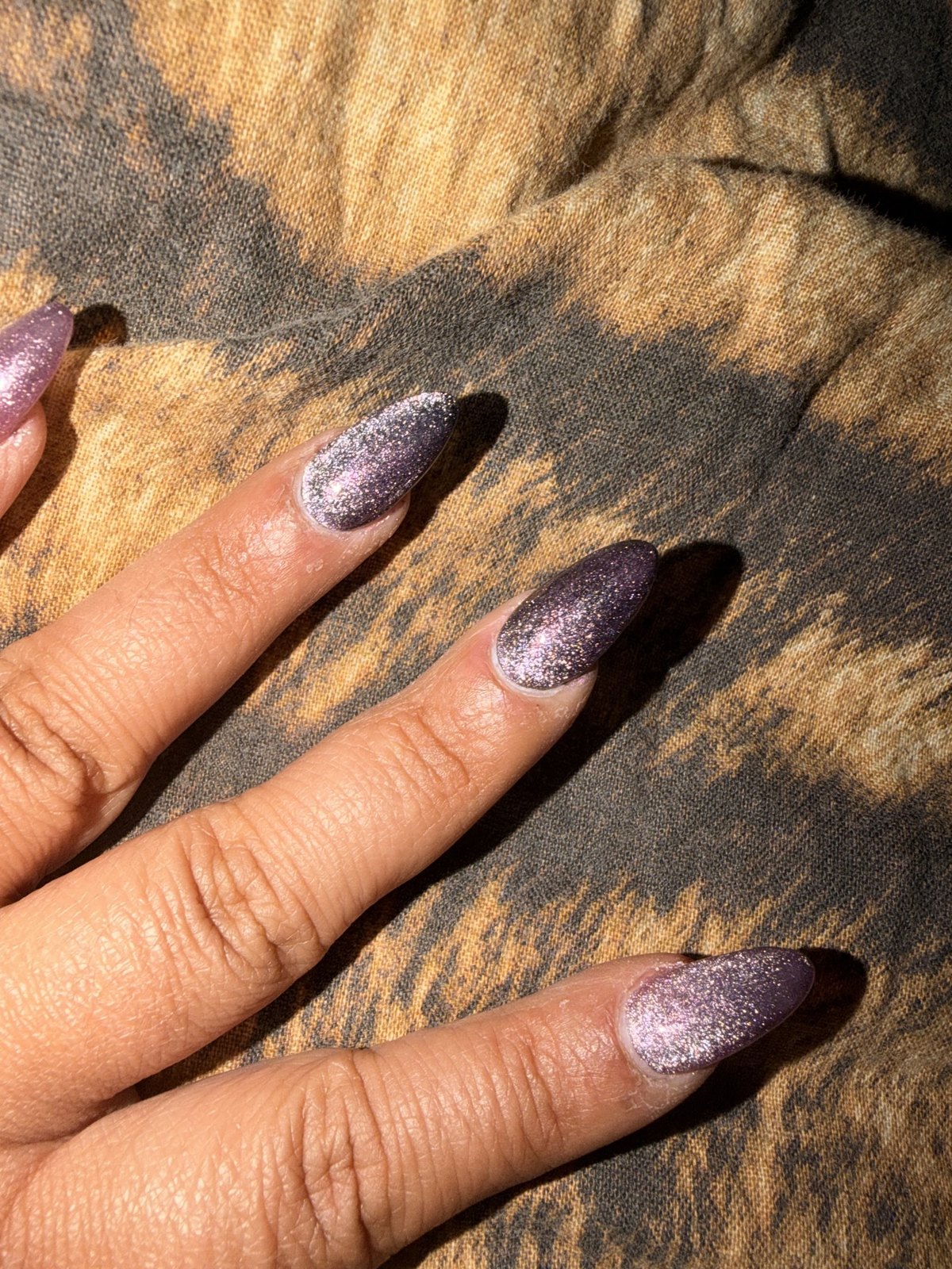Amandelvormige nagels met paarsgrijze glitter op een stof met dierenprint