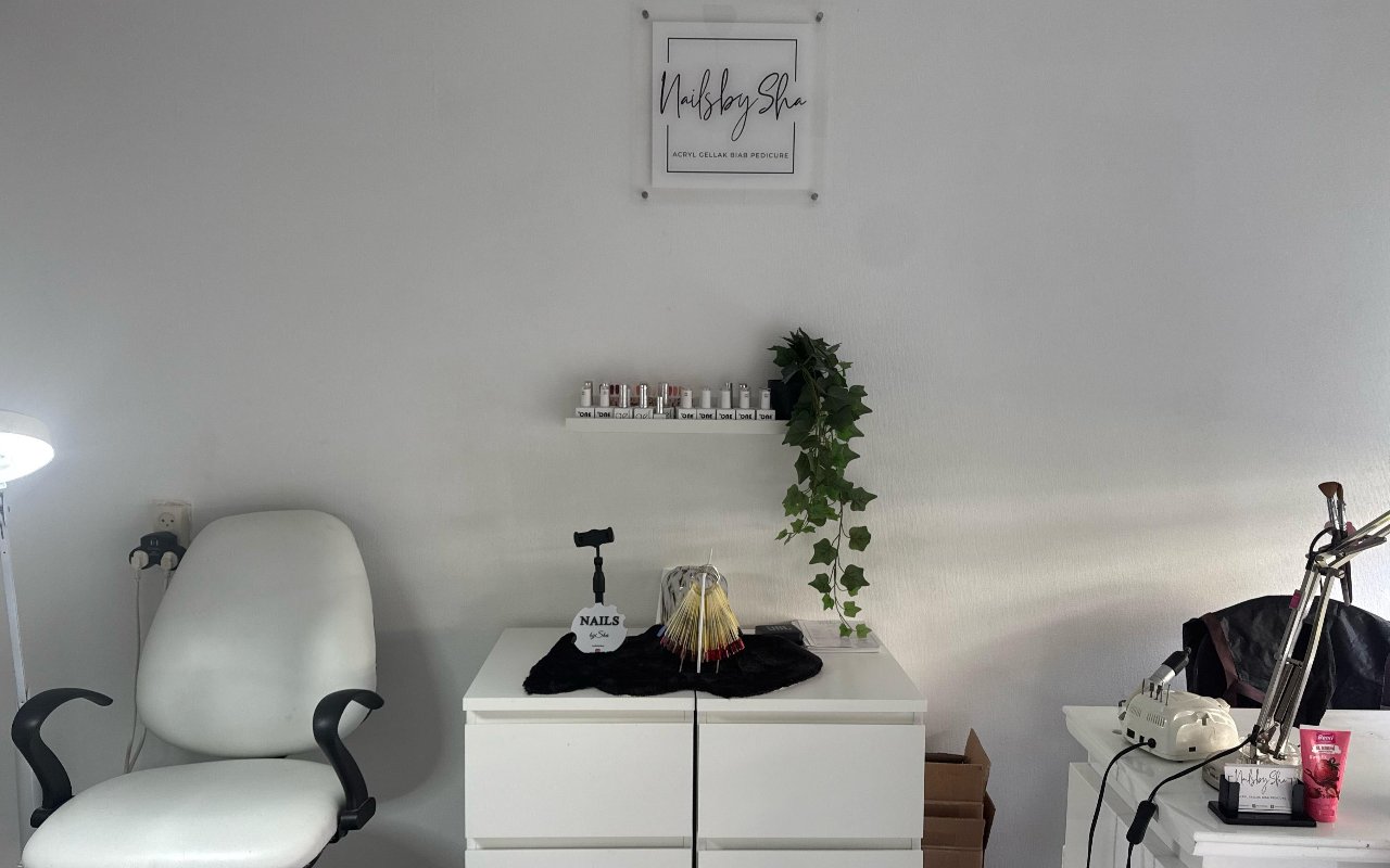 Het NailsBySha-bord boven de witte behandelstoel