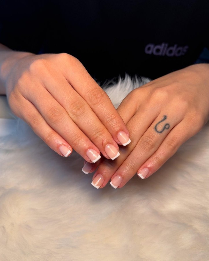 Korte nagels met een witte French op een wit vachtje